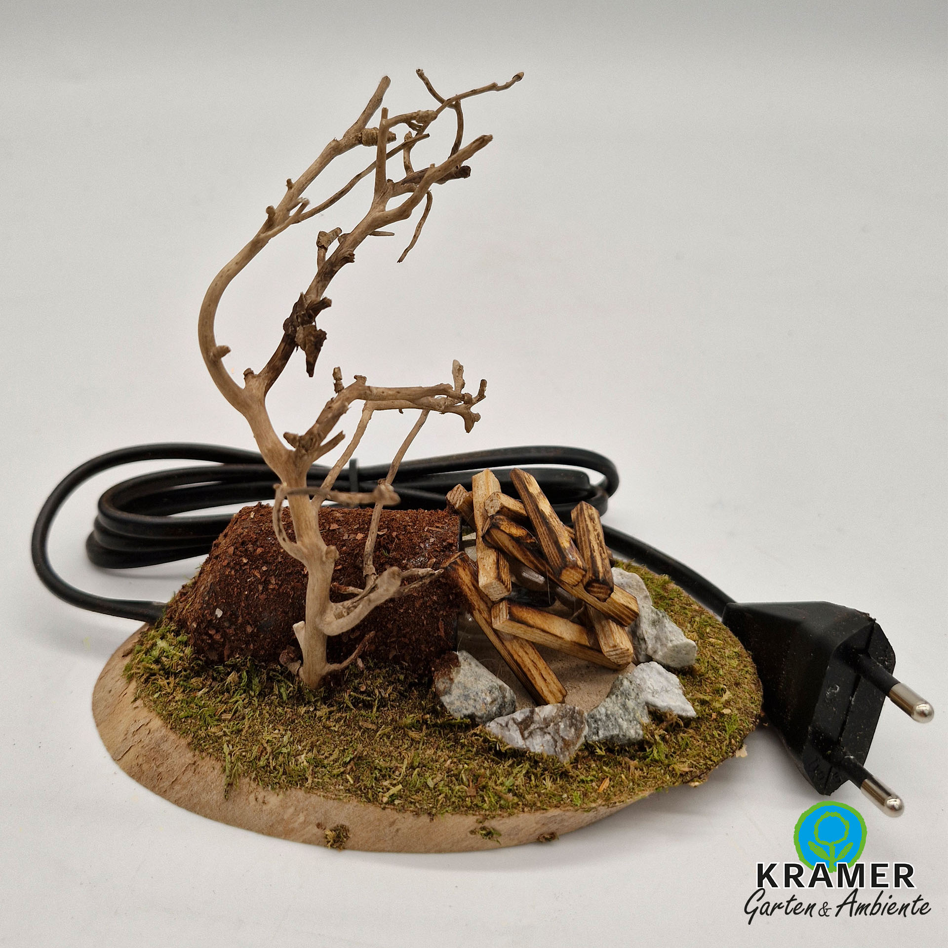 Baum und Lagerfeuer auf bemooster Holzplatte