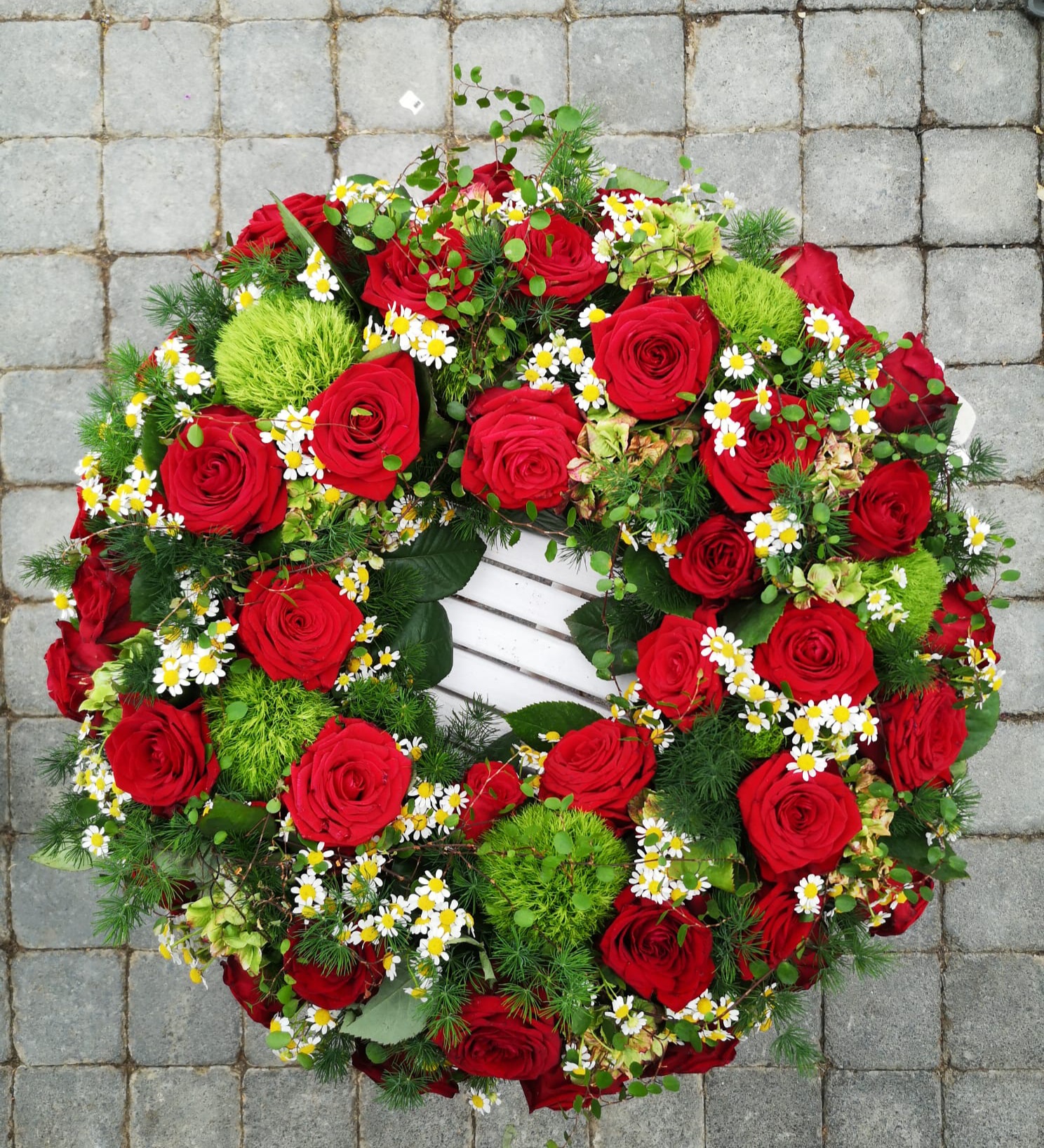 rndgesteckter trauerkranz mit vielen roten rosen