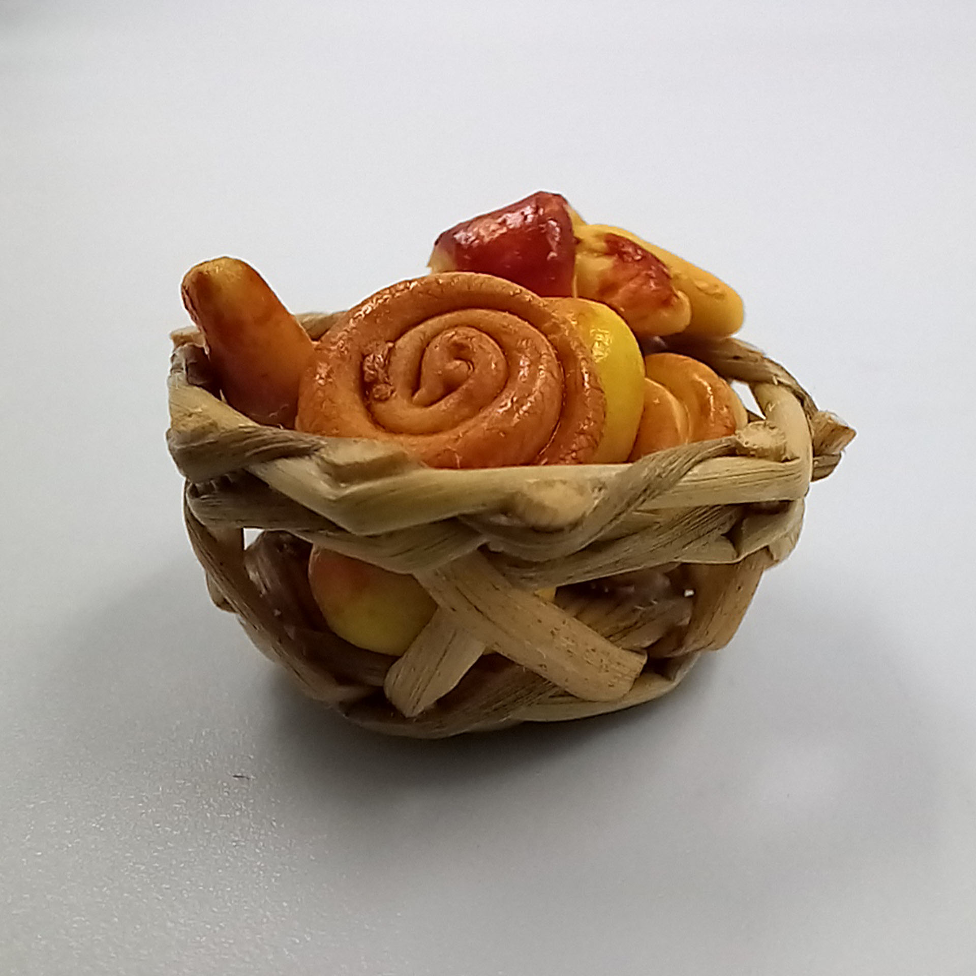 naturfarbener, geflochtener Korb mit Brötchen, Hörnchen, Schnecken