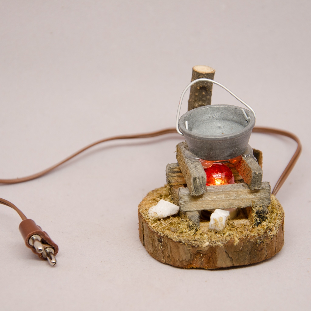 Feuerstoß mit Zinntopf auf Holzplatte