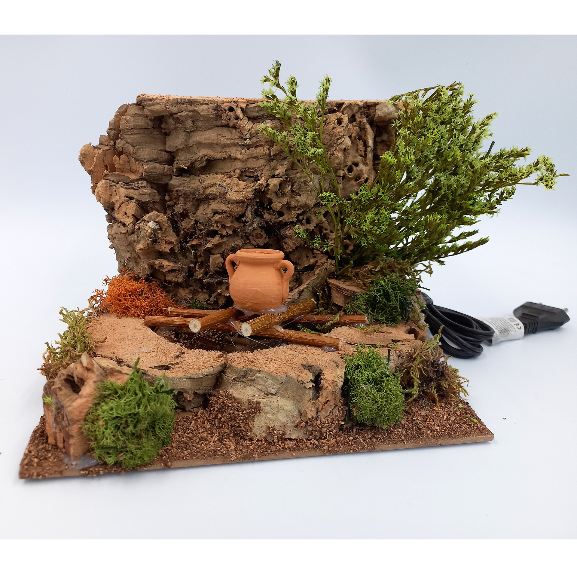 Lagerfeuer aus Kork und Naturmaterial auf Platte, Tonkrug über Feuer