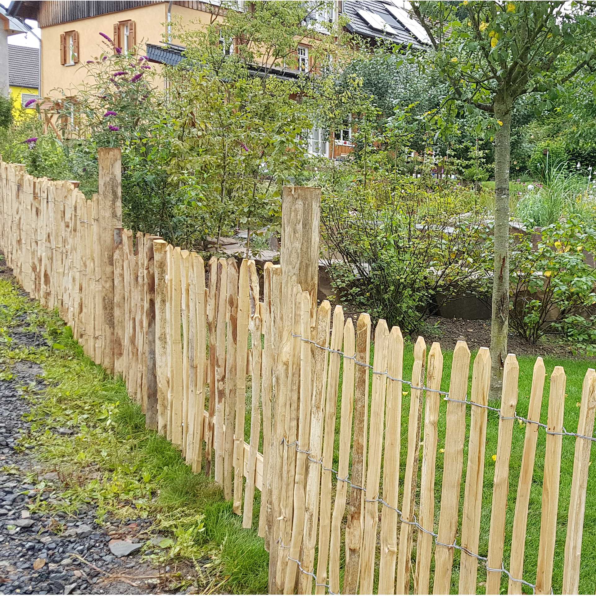 langer zaun führt an großem garten vorbei und trennt diesen vom weg , Holzzaun, Zäune, Gartenzaun, Holzlatten, Staketenzaun
