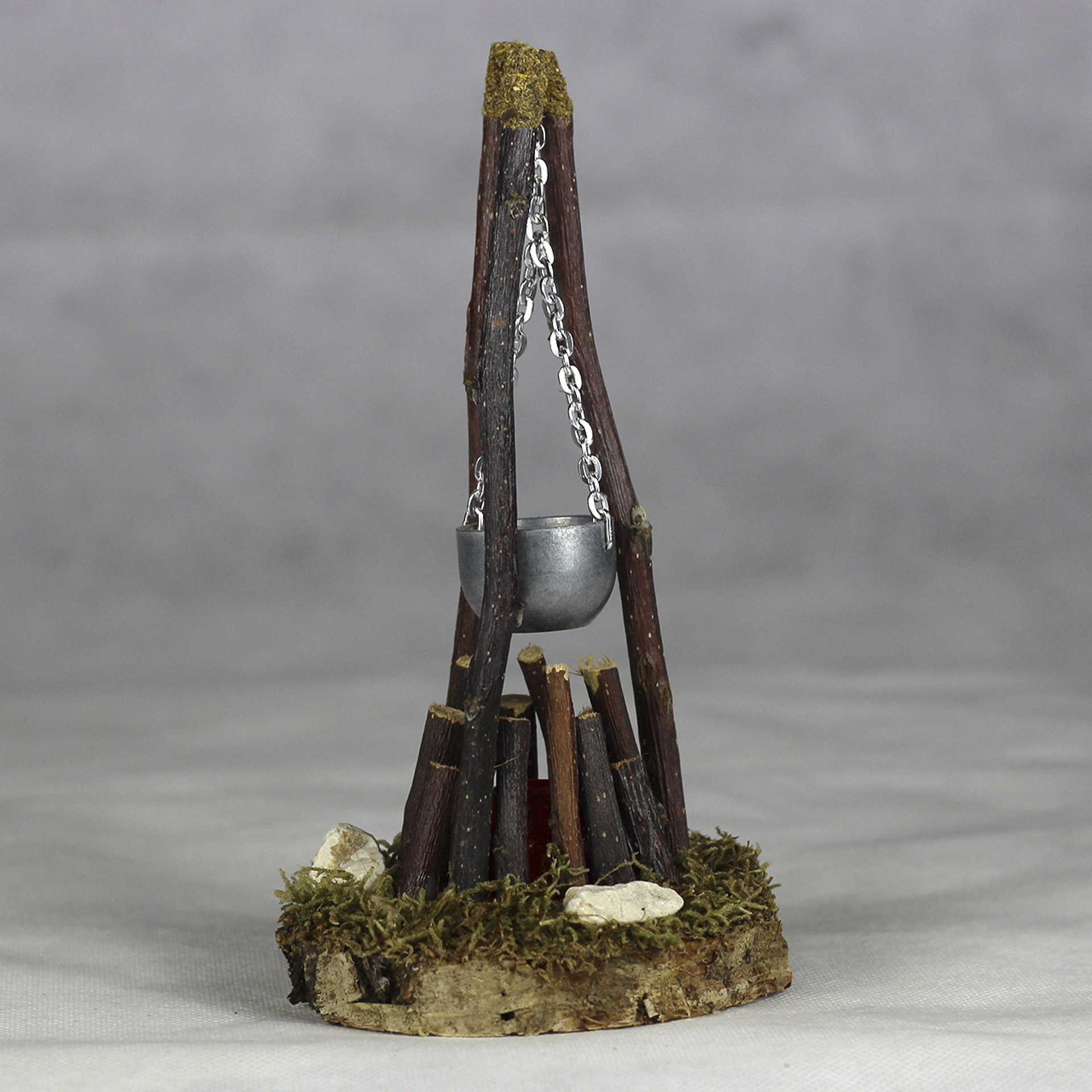 Holzstapel als Lagerfeuer, Dreibock mit darüber hängendem Kessel